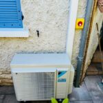 installation d'une pompe à chaleur air-air par PC Rénovation au sol devant un mur extérieur d'une maison.